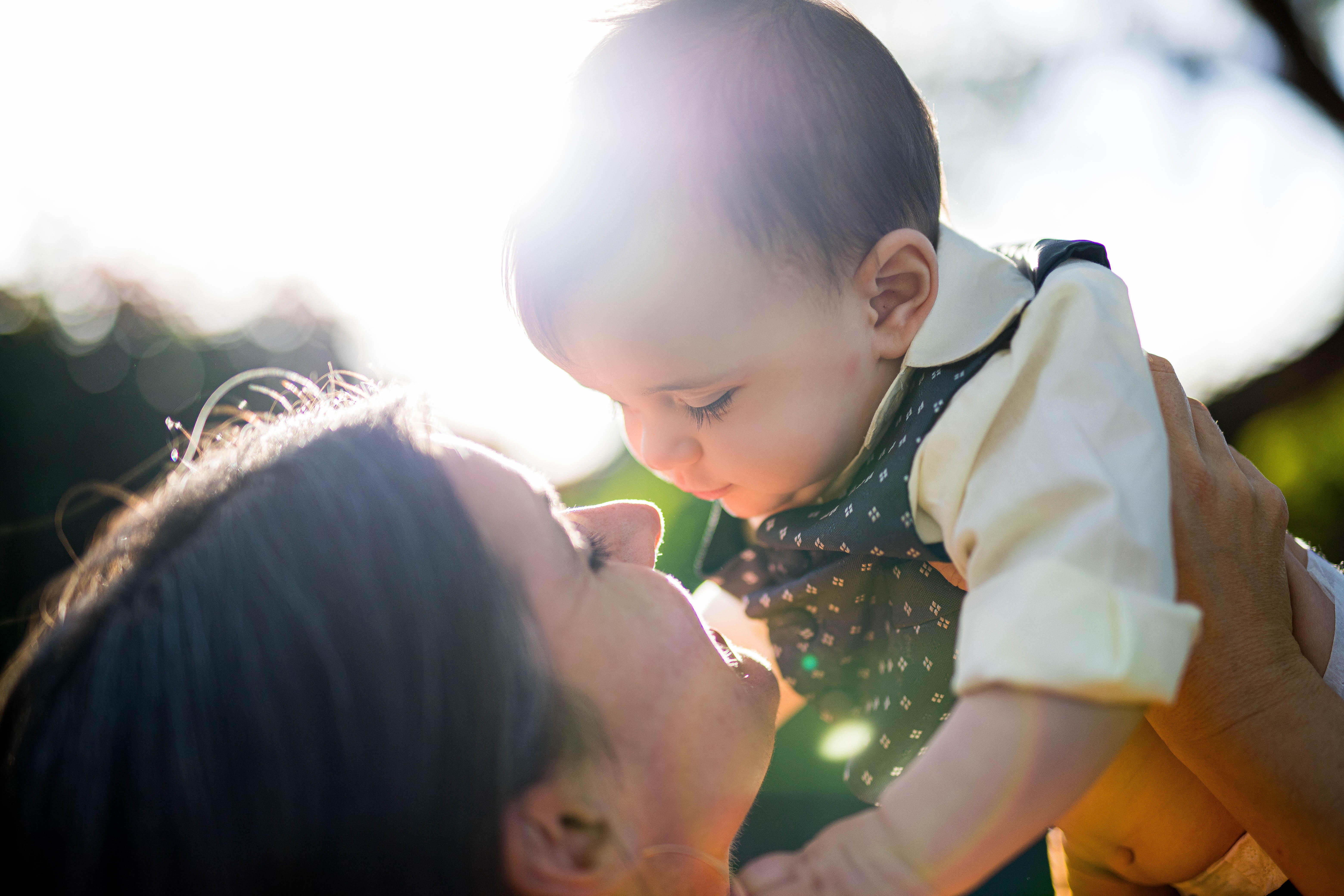 A young mother lifting her baby in warm sunlight
